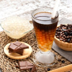 Fotografía de bebidas para marca de zumos y refrescos en Barcelona: Bubble Fruit de General Fruit Vaso de bubble tea oscuro con perlas, chocolate y granos de café para General Fruit.