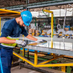 Operario de Thyssenkrupp Materials inspeccionando plancha de acero inoxidable en nave industrial — fotografía industrial Barcelona